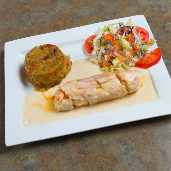 Mofongo with shrimp in cream sauce and a side salad on a white rectangular plate.