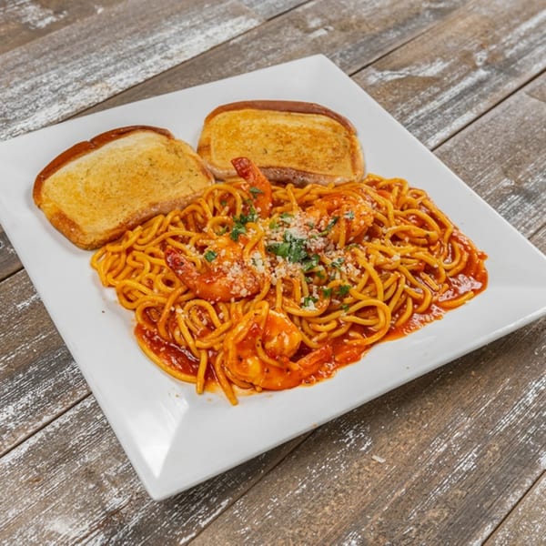 Shrimp spaghetti with red sauce, parmesan, parsley, and two slices of garlic bread on a white plate.